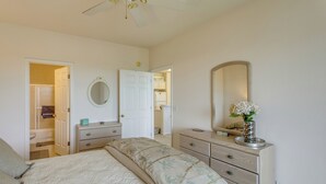 Une chambre à coucher comprenant un lit, une commode, un miroir et une porte donnant sur une autre pièce.