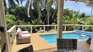 Ein Poolbereich mit Korbmöbeln, einem Pool und üppiger Bepflanzung.