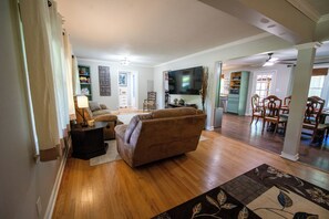 A living room with a sofa, a TV, and a dining area with chairs and a table. - Aiken Equestrian Dog Friendly  Bruce's Field (Aiken)