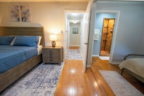 A bedroom with a bed, bedside table, lamp, and a hallway leading to a bathroom. - Aiken Equestrian Dog Friendly  Bruce's Field (Aiken)