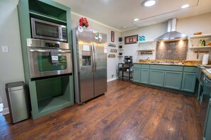A kitchen with a built-in oven, microwave, and refrigerator, wooden flooring, and green cabinetry. - Aiken Equestrian Dog Friendly  Bruce's Field (Aiken)