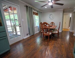 A dining area with a wooden table and chairs, a ceiling fan, and a clock on the wall. - Aiken Equestrian Dog Friendly  Bruce's Field (Aiken)