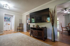 A living room with a flat-screen TV, wooden furniture, a large vase, and a dining area with chairs. - Aiken Equestrian | Dog Friendly |Bruce's Field (Aiken)