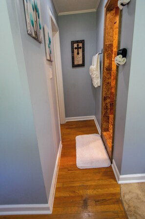A narrow hallway with a wooden floor leading to a bathroom with a shower area. - Aiken Equestrian | Dog Friendly |Bruce's Field (Aiken)