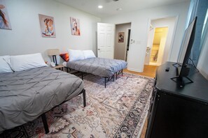 Un dormitorio con dos camas, una alfombra, un escritorio y un televisor.