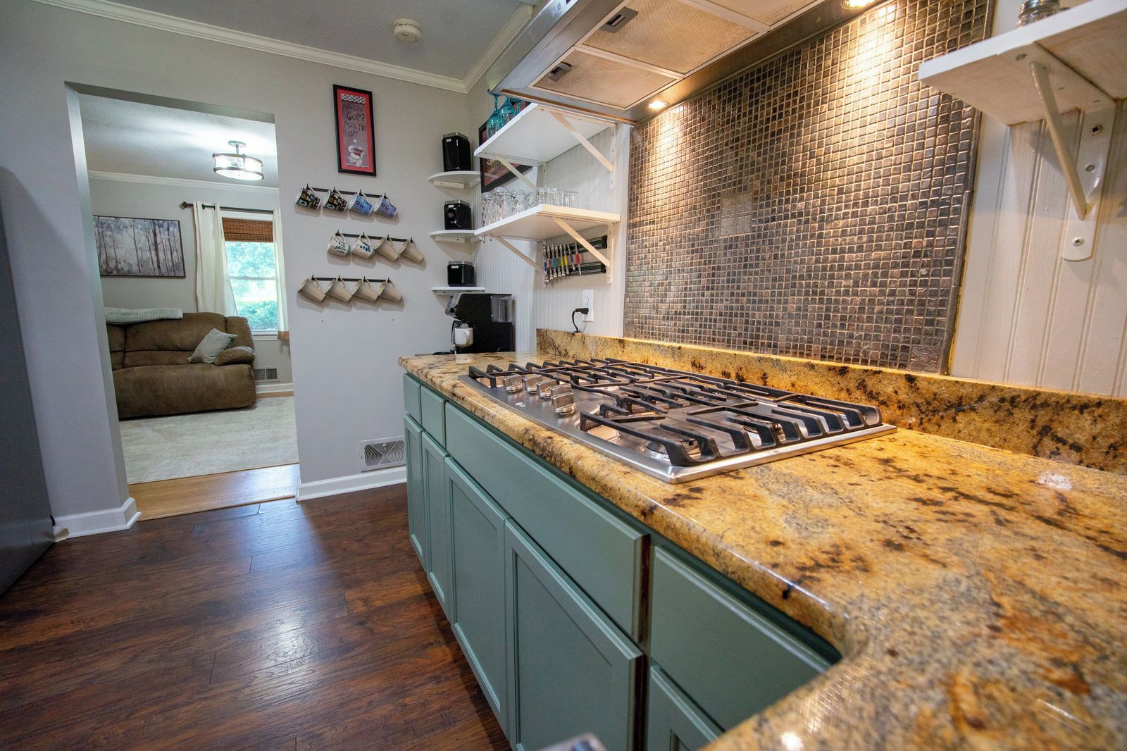 Una cocina con estufa a gas, encimera de granito y salpicadero con diseño de mosaico.