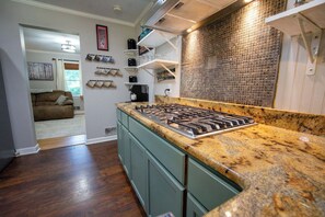 A kitchen with a gas stove, granite countertop, and a backsplash with a mosaic tile pattern. - Aiken Equestrian | Dog Friendly |Bruce's Field (Aiken)