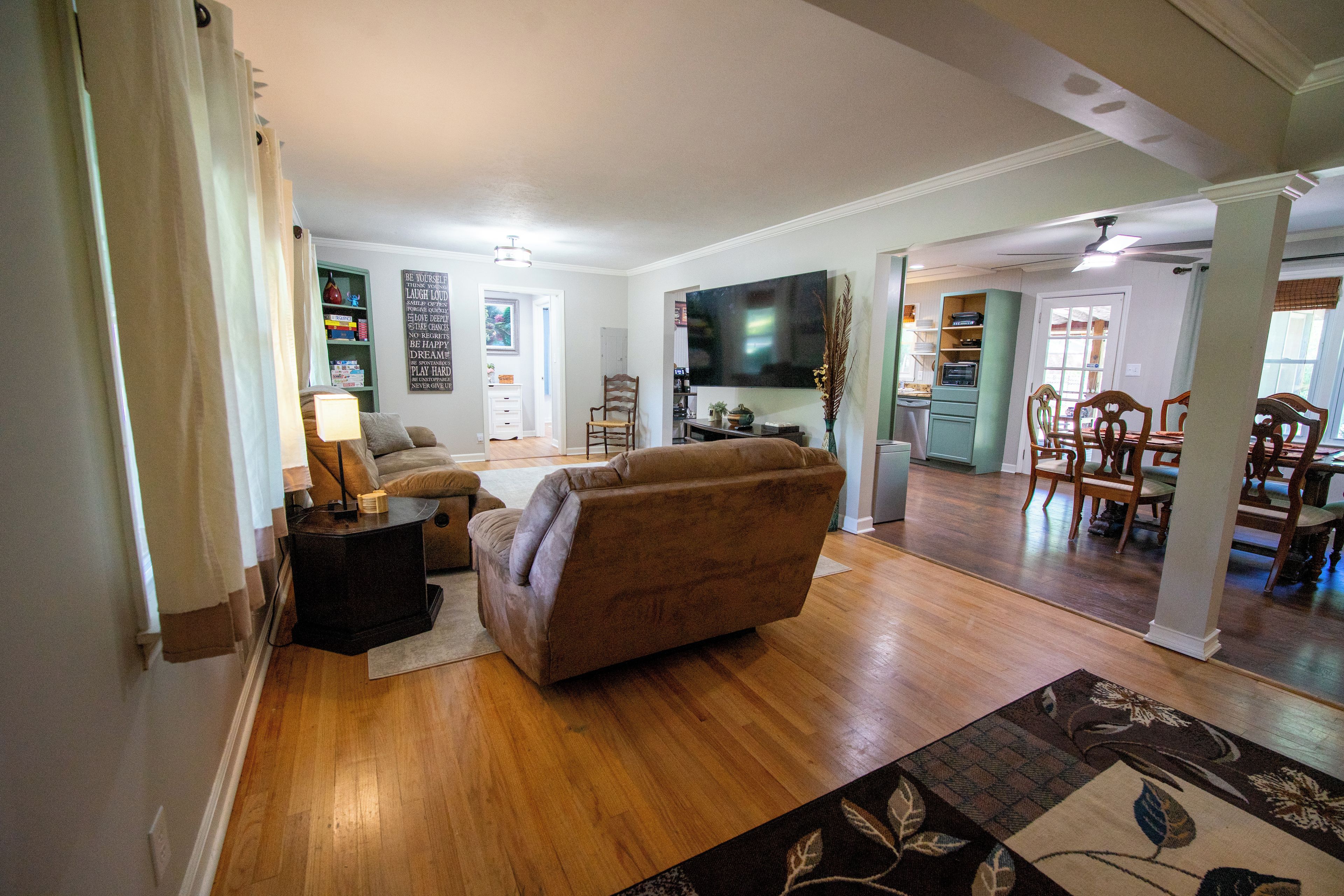A living room with a sofa, a TV, and a dining area with chairs and a table.