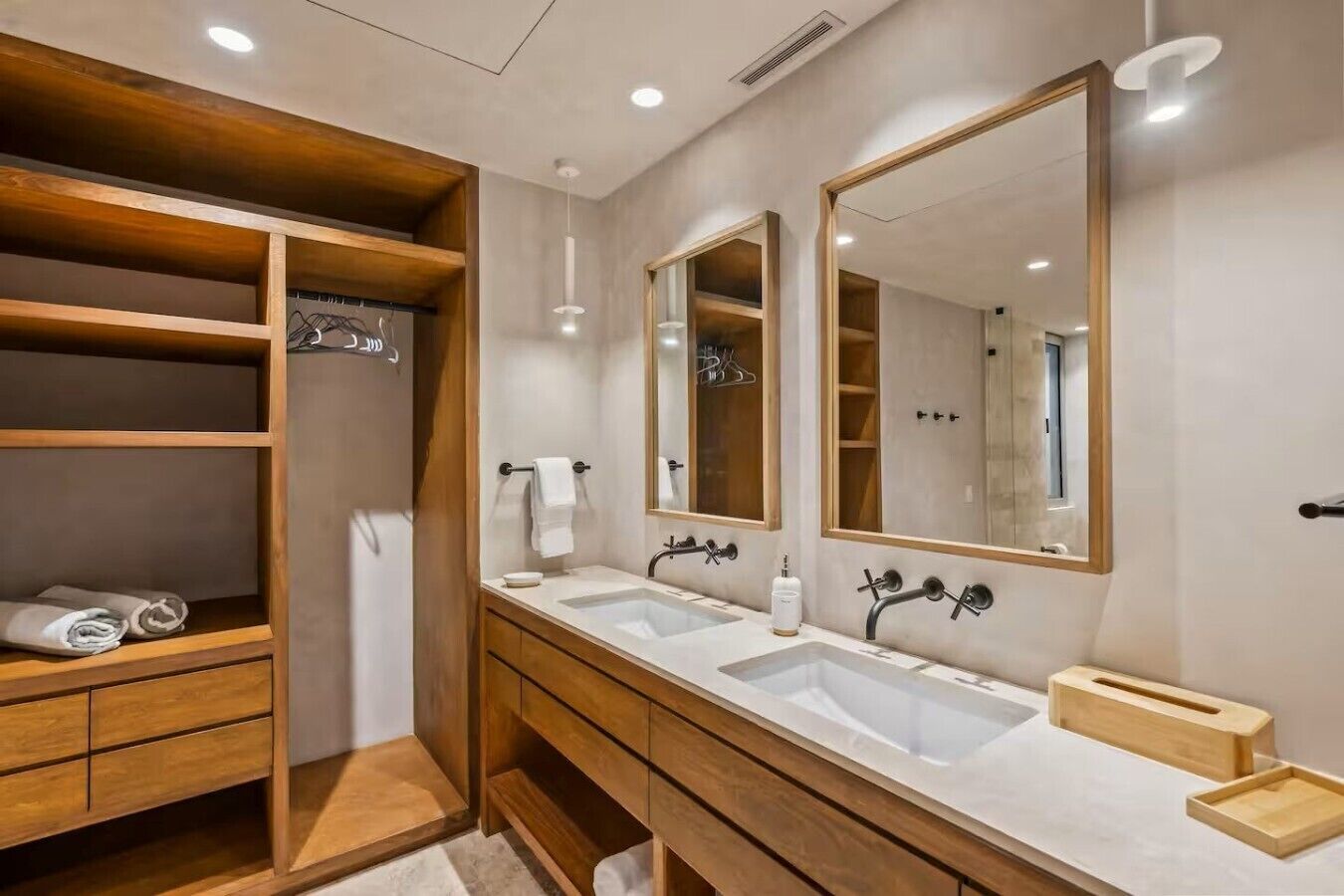 Un bagno moderno con due lavabi, un mobile contenitore in legno e un grande specchio.
