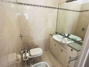 A bathroom with a toilet, sink, and shower area. - Apartment Rubens by Interhome (Rapallo)