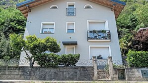 Un edificio de varios pisos con fachada simétrica, entrada central y balcones con barandillas metálicas.