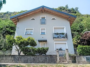 A multi-story building with a symmetrical facade, a central entrance, and balconies with metal railings. - Boscolago by Interhome (Porto Ceresio)