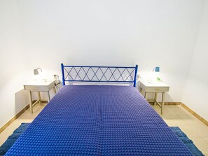 Una habitación con una cama, dos mesitas de noche y un escritorio.