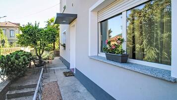 A modern building with a balcony, a small garden, and a window with a plant.