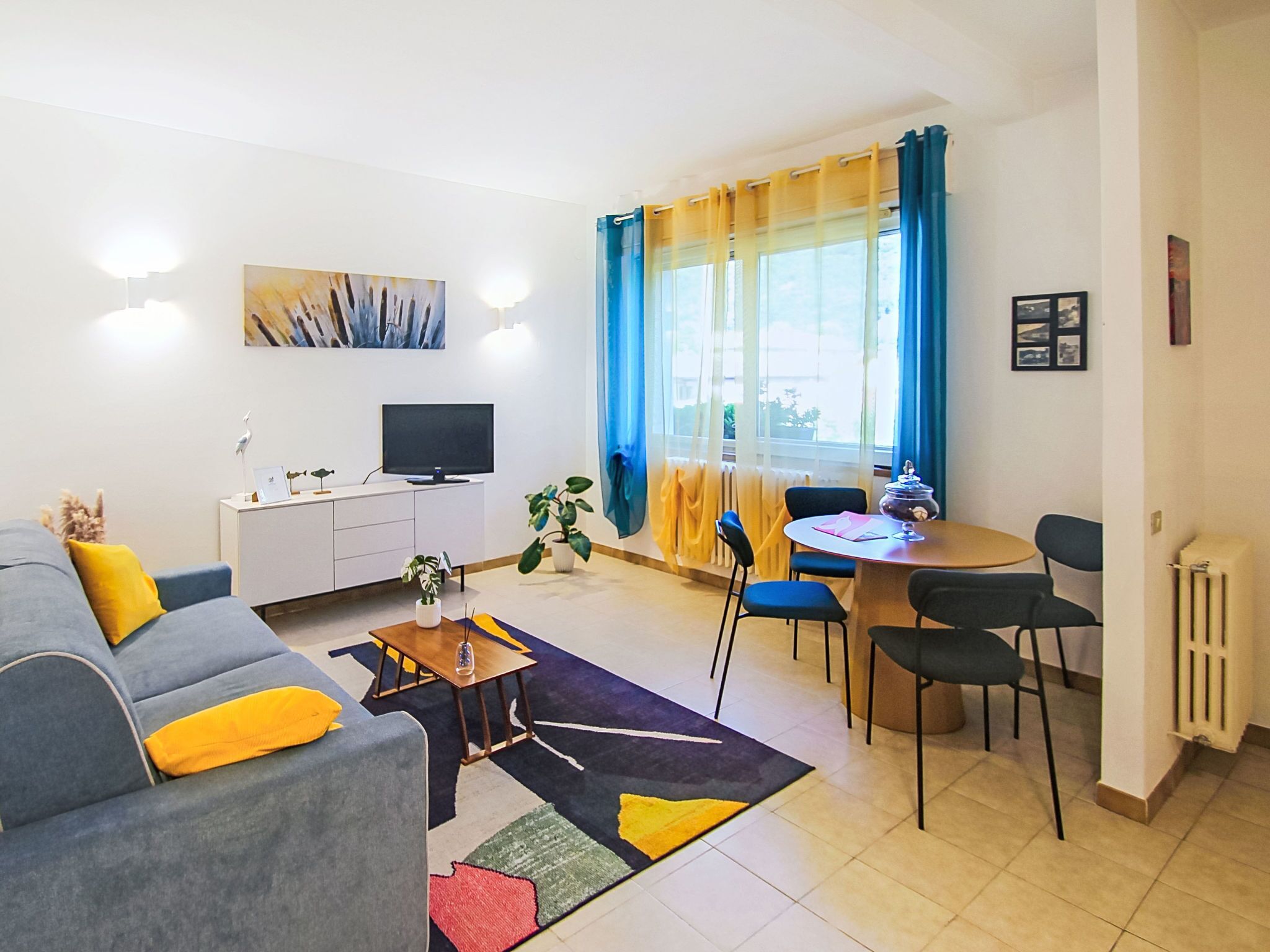 Un salon moderne comprenant un canapé, une table basse, un téléviseur et un coin repas avec des chaises et une table.