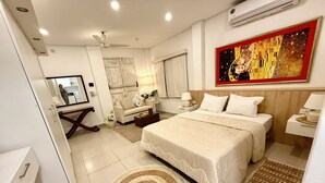 A hotel room with a bed, bedside tables, a ceiling fan, a painting, and a mirror.