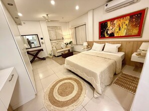 Habitación de hotel con cama, mesitas de noche, ventilador de techo, un cuadro y un espejo.