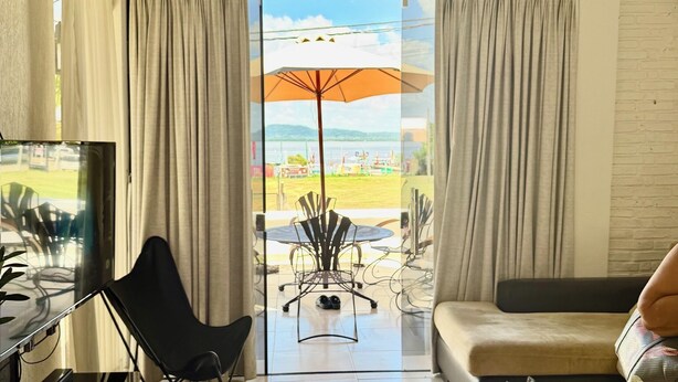 A room with a large window, a ceiling fan, a TV, and a dining table with chairs.
