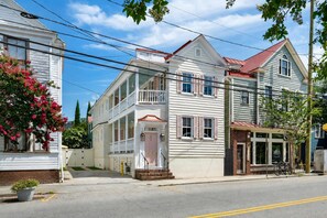 A two-story building with a balcony, a garage, and a small porch. - Designer Retreat | Pool + 4 King Suites (Charleston)
