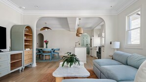 Un salon moderne comprenant un canapé, une table basse, un téléviseur et un coin repas avec des chaises et une table.