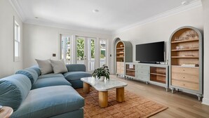 Un salon moderne avec un canapé d’angle, une table basse, un téléviseur et une bibliothèque intégrée.