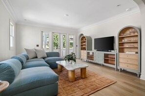 Ein modernes Wohnzimmer mit einem Ecksofa, einem Couchtisch, einem Fernseher und einer integrierten Bücherreol.