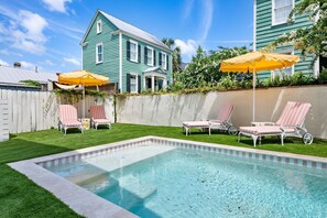 A backyard with a swimming pool, two lounge chairs, and a house. - Designer Retreat | Pool + 4 King Suites (Charleston)