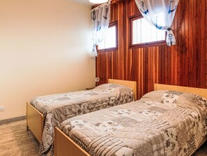 Une pièce avec deux lits en bois, une fenêtre avec des rideaux et un mur en bois.