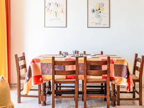 Une table à manger recouverte d’une nappe patchwork, entourée de chaises en bois dotées d’assises rembourrées.