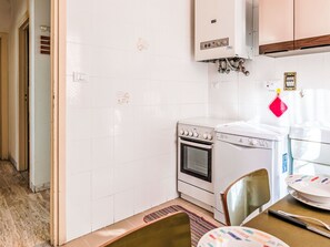 Une cuisine compacte équipée d’une cuisinière, d’un four et d’un lave-linge.