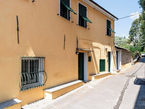 A two-story building with a yellow facade, a balcony with metal railings, and a small entrance with a door. - Apartment Oliver by Interhome (Dolcedo)