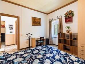 A bedroom with a bed, a desk, a chair, a radiator, and a window with curtains. - Apartment Oliver by Interhome (Dolcedo)