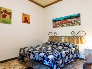 A bedroom with a bed, a nightstand, and two paintings on the wall. - Apartment Oliver by Interhome (Dolcedo)