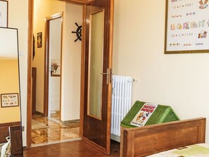 A room with a bed, a radiator, a door with a window, and a wall with a calendar and a poster. - Casa Mandarino by Interhome (Bordighera)