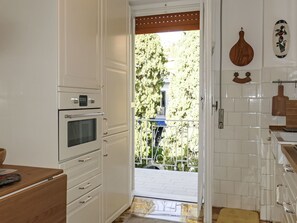 A kitchen with white cabinets, a built-in oven, and a wooden cutting board on the counter. - Casa Mandarino by Interhome (Bordighera)