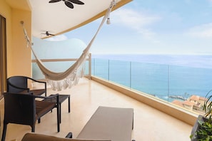 Ein Balkon mit einer Hängematte, zwei Stühlen, einem Tisch und Blick aufs Meer.
