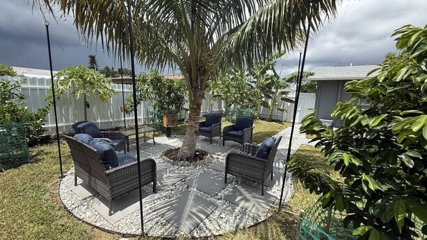 An outdoor patio area with wicker furniture, a central tree, and a stone fire pit. - Viceroy 3 bedrooms (Cape Coral)