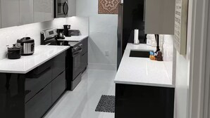 A modern kitchen with black and white cabinetry, stainless steel appliances, and a central island. - Viceroy 3 bedrooms (Cape Coral)