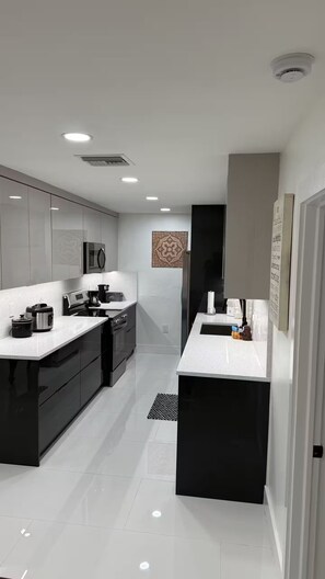 A modern kitchen with black and white cabinetry, stainless steel appliances, and a central island. - Viceroy 3 bedrooms (Cape Coral)