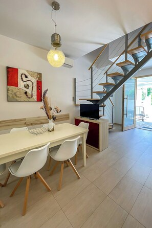 A modern interior with a dining area, a staircase, and a TV on a cabinet. - Vacation home Volme by Interhome (Pula/Banjole)