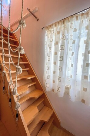 A wooden staircase with a rope ladder on the left, and a window with patterned curtains on the right. - Vacation home Volme by Interhome (Pula/Banjole)