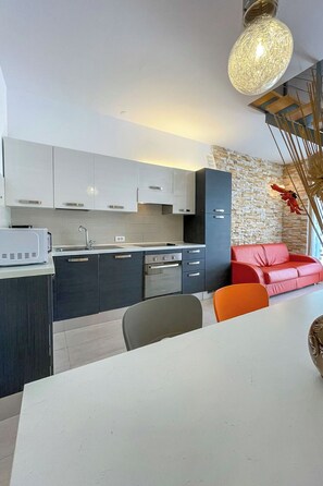 A modern kitchen with white cabinets, a built-in oven, and a stone accent wall. - Vacation home Volme by Interhome (Pula/Banjole)