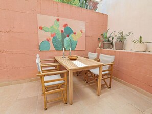 Ein Holztisch mit Stühlen, ein Sukkulentenbild an der Wand und Topfpflanzen.