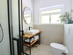 Ein Badezimmer mit Waschbecken, Spiegel, Fenster und Toilette.