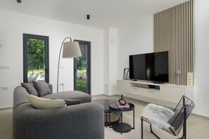 Una sala de estar moderna con un sofá, una mesa de centro, un televisor y una silla.