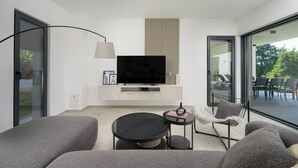 A modern living room with a flat-screen TV, grey sofas, a small round table, and a side table with a lamp. - Villa Yamila (Istria - Žminj) (Žminj)