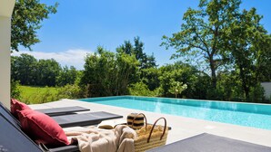 A poolside area with lounge chairs, a towel, and a woven basket. - Villa Yamila (Istria - Žminj) (Žminj)