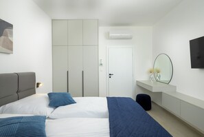 Un dormitorio con cama, mesita de noche, espejo, armario y aire acondicionado.