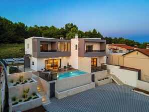 Une maison moderne à deux étages, dotée d’une piscine, d’un espace extérieur aménagé et d’un jardin bien entretenu.
