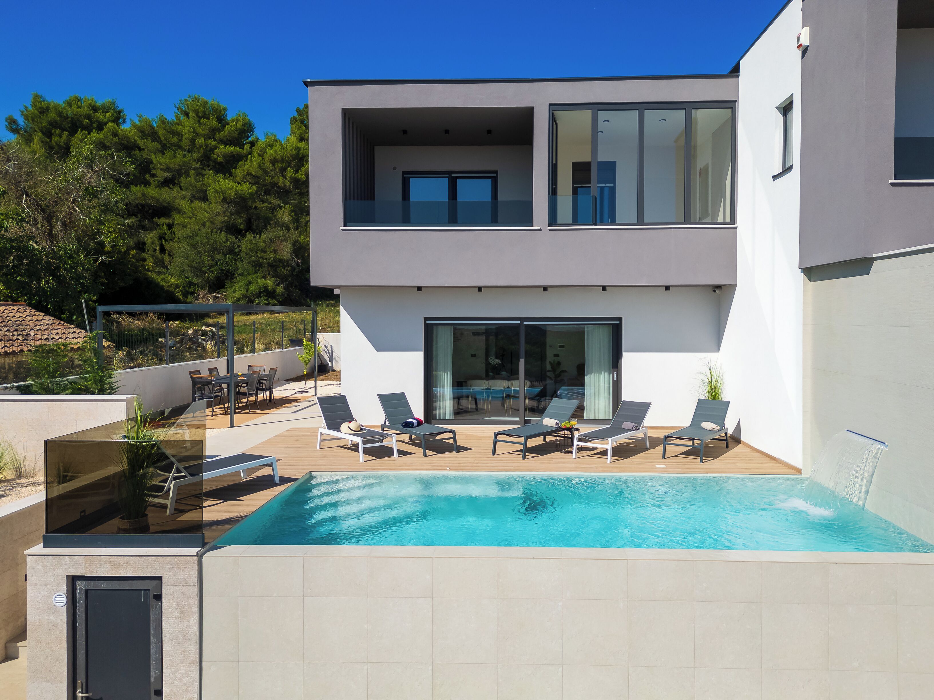 Ein modernes, zweistöckiges Haus mit Pool, Außenbereich und Blick auf die umliegende Natur.